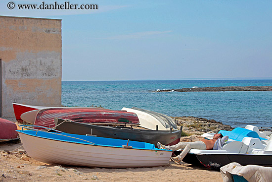 man-sleeping-by-boats.jpg