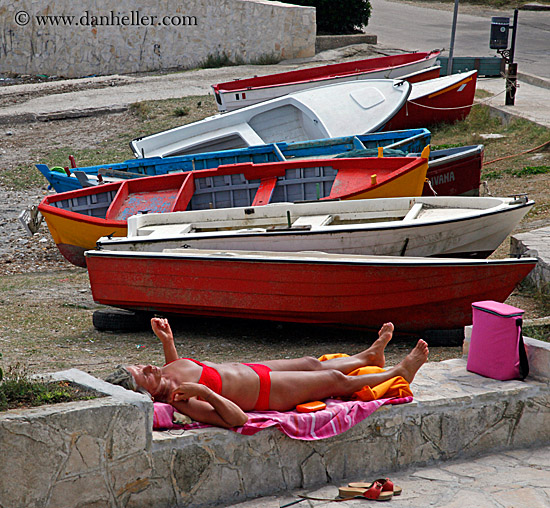 woman-sunbathing-by-colorful-boats.jpg