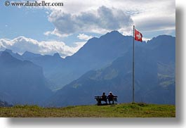 images/Europe/Switzerland/Kandersteg/LakeOeschinensee/couple-on-bench-by-swiss-flag.jpg